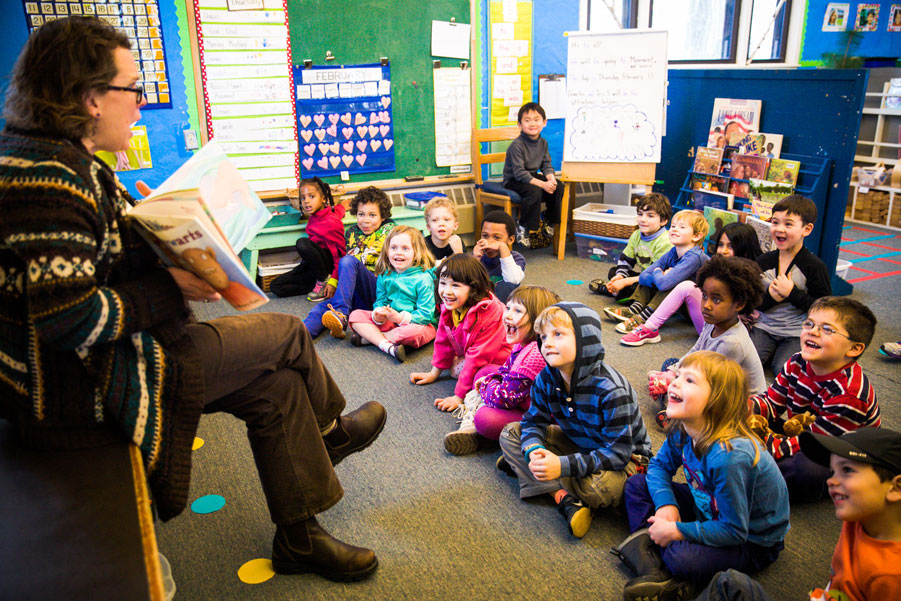 Kids listening to a book being read by the teacher
